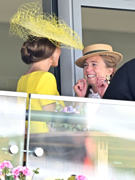 Kate Middleton in a yellow hat and dress speaking to a smiling woman in a hat